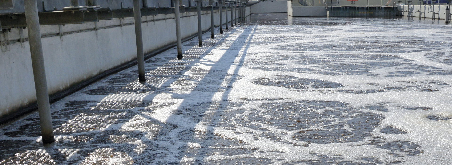 Foto: Das Belebungsbecken - ein längliches großes Betonbecken mit schäumendem Wasser